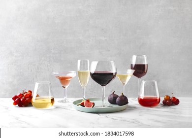Various types of wine in different sort of glassware standing on a marble table surface, wine tasting concept