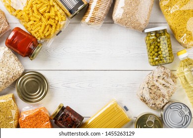 Various Uncooked Cereals, Grains, Pasta And Canned Food On A White Wooden Table. Ingredients For Cooking. Frame Background With Copy Space.