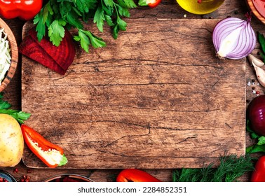 Various uncooked vegetables, herbs and spices for healthy cooking and cutting board on rustic kitchen wooden table, top view. Preparation vegetarian cabbage, beetroot, tomato soup - Powered by Shutterstock