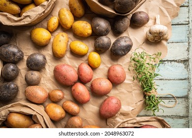 Various varieties of new colorful, white, red and purple potatoes in paper bags on white wooden background, top view - Powered by Shutterstock