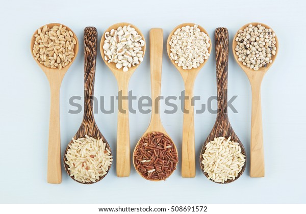 Various varieties of rice and\
wholegrains in spoon on wooden table background. Wheat, barley,\
millet, oats, rice, coarse grain, sorghum, lotus\
seed.