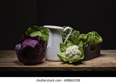 various vegetable composition with salad and cauliflower and red cabbage white water jug on boards rustic lrgno and black