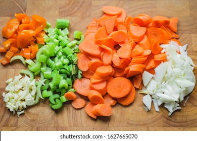 Various Vegetables Cut On A Wooden Board. Ready To Cook. Carrots, Celery Sticks, Garlic, Onions And Peppers.