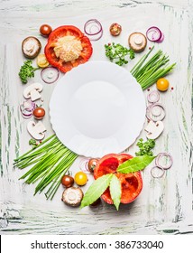 Various vegetables and seasoning cooking  ingredients around blank plate on light  rustic wooden background, top view composing. Healthy eating and diet food concept. 