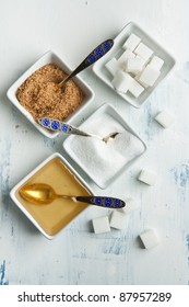 Various Of White And Brown Sugar With Honey In White Plates On White Wooden Table