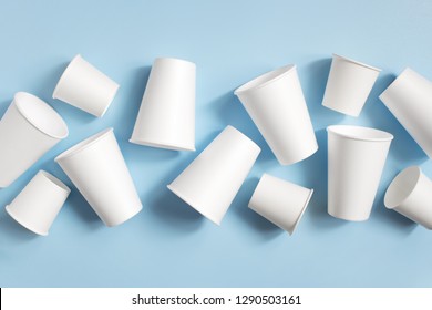 Various white disposable cups on the light blue background, top view