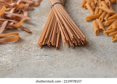 Various Wholegrain Pasta, Tagliatelle, Spaghetti And Penne Rigate, Healthy Noodle Alternative With More Fiber, Gray Stone Background, Copy Space, Selected Focus, Very Narrow Depth Of Field