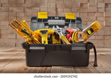 Various Work Tools In Little Black Toolbox. On Background Of Pile Wooden Beams. - Shutterstock ID 2059192742
