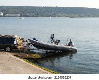 Varna, Bulgaria - July, 23, 2022: Men Pulling A Boat Onto A Car Trailer In The Seaport