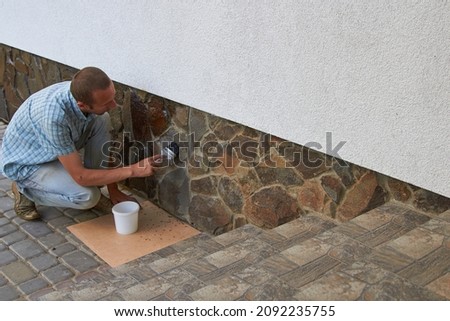 varnish the stone on the house,stone with foundation man applies varnish with a brush