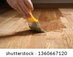 Varnishing lacquering parquet floor by paintbrush - second layer. Home renovation parquet. Varnish paintbrush strokes on a wooden parquet. Application of a highly glossy parquet lacquer