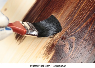 Varnishing a wooden shelf using paintbrush