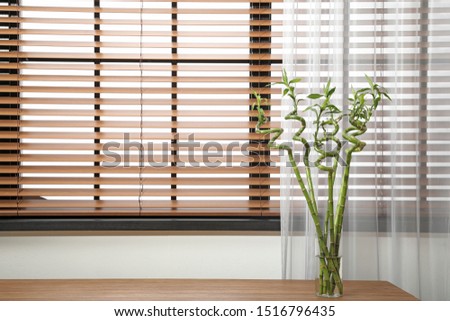 Vase with bamboo stems on wooden table indoors, space for text