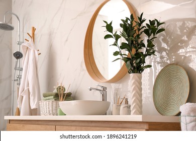 Vase with beautiful branches and toiletries near vessel sink in bathroom. Interior design
