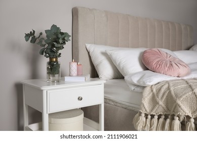 Vase With Beautiful Eucalyptus Branches, Book And Candles On Nightstand In Bedroom