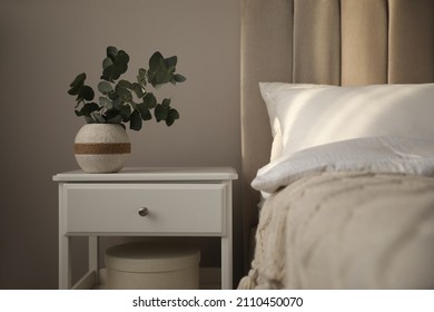 Vase with beautiful eucalyptus branches on nightstand in bedroom