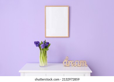 Vase With Beautiful Flowers, Word DREAM On Table And Blank Photo Frame On Color Wall