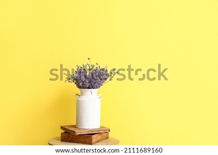 Vase with beautiful lavender flowers on table against color background