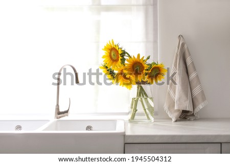 Vase with beautiful yellow sunflowers in kitchen