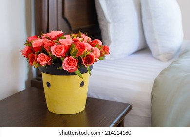 Vase Of Flowers On A Side Table Near A Bed.