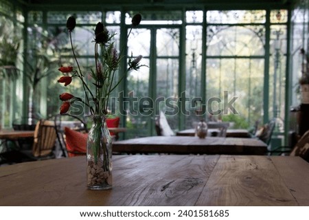 A vase of flowers on a wooden table in a wrought iron gazebo. High quality photo