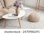 Vase with lilac flowers and magazine on coffee table in living room