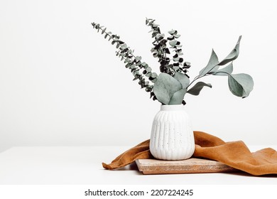Vase with natural eucalyptus leaves on wooden stand with copy space, scandinavian interior style, home eco decoration