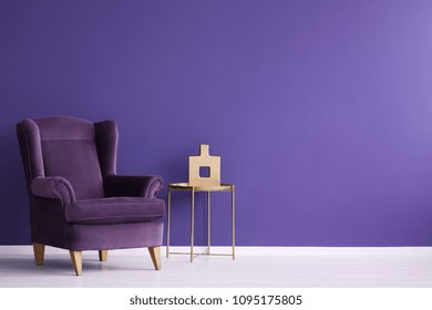 Vase On Gold Table Next To A Velvet Purple Armchair In Minimal Violet Living Room Interior With Copy Space