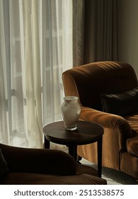A vase on a table in front of a window. Autumn interior of a Mayfair London apartment. Coziness in the photo