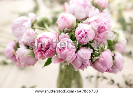 vase of peonies in the foreground. soft focus. Workshop florist, making bouquets and flower arrangements. Woman collecting a bouquet of flowers.