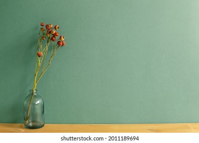 Vase Of Red Dry Flowers On Wooden Table. Green Wall Background. Home Interior