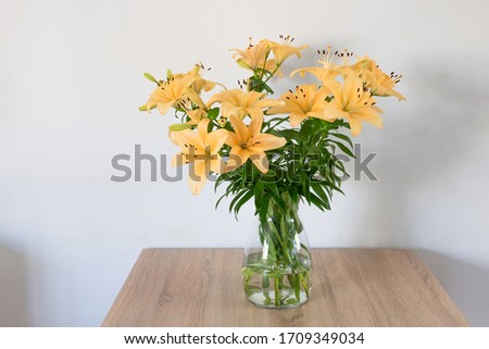 Vase with soft pastel colored lily (Latin: Lilium) flowers on a table
