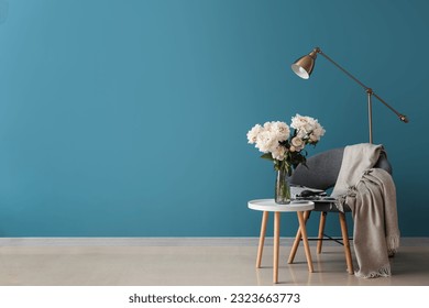 Vase of white peonies with coffee table, chair and floor lamp near blue wall - Shutterstock ID 2323663773