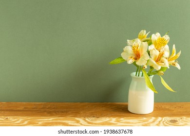 Vase Of Yellow Alstroemeria Flowers On Wooden Table. Green Background. Home Interior