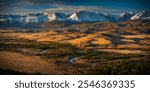 Vast Altai mountains landscape during autumn, showcasing golden plains and snow-capped peaks under dramatic skies. Serene atmosphere with natural beauty and tranquility.