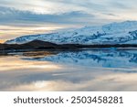 Vast body of water and snow capped peaks in icelandic setting, Scandinavian frozen lake within the highlands making northern winter panorama at sunset. Snowy pastures in magnificent landscape.