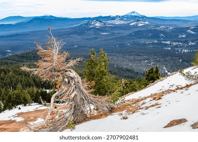 A vast, expansive panoramic view of distant mountain ranges and valleys, observed from the high vantage point of the Crater Lake National Park rim in Oregon