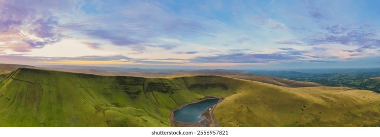 Vast green hills and a serene lake under a colorful sky in Wales during twilight hours - Powered by Shutterstock