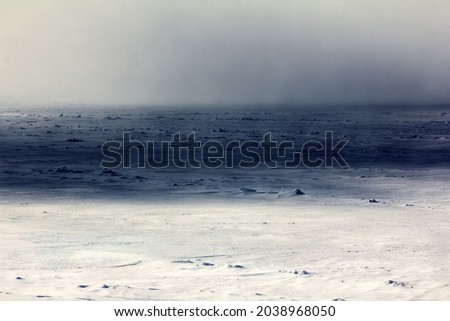  Vast ice field (giant floe) made with perennial ice at latitude of 86 degrees north latitude. In second ground deep shadow of cloud and watery sky over regional polynya. Arctic Ocean. Helicopter view