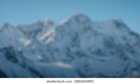 A vast, imposing mountain range covered in snow and ice, reaching towards a bright, cloudless sky.