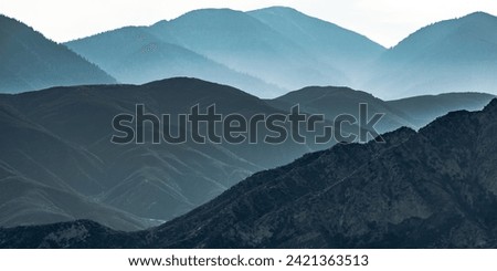 Vast mountain ridge in Ontario California. View of the vast mountain ridge in Ontario, California beneath a white sky. The mountain have numerous steep and rugged slopes.