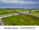 A vast plain, green arable fields and meadows. In the center of the frame there is a large communication junction and a fork in expressways. View from a great height. Photo from the drone.