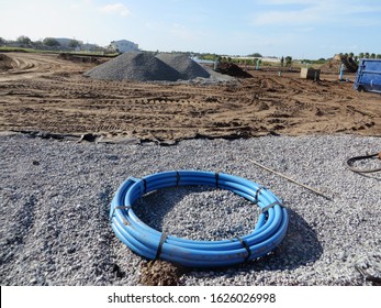 
Vast Residential Construction Site, Florida.	Blue Cable Coiled On Field Of Gravel With Land Clearing And Grading In Background. 