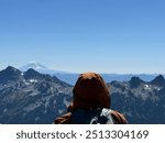 “Lost in the vastness: A hiker gazes towards Mount Rainier, dwarfed by nature’s grandeur.”