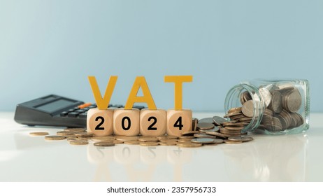 VAT in 2024 concept. VAT wooden letter and 2024 number on wooden block and glass coin jar with  calculator. Value Added Tax.