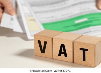 VAT settlement in Poland, abbreviation for value added tax, tax on goods and services paid by sellers and buyers, finance concept, written on wooden blocks and stack of held documents, bureaucracy - Shutterstock ID 2394567091