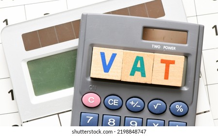 VAT Word Arranged With Wooden Letters On The Calculator Screen. Settlement VAT In Poland.