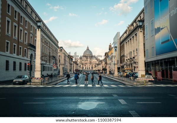 Vatican City, Vatican - Oct 6, 2017: Road traffic\
on the street in front of St. Peter\'s Square and St. Peter\'s Square\
Basilica. It is the famous travel destination of tourist visiting\
Rome, Italy.