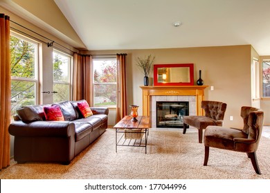 Vaulted ceiling living room with soft carpet floor and cozy fireplace. Furnished with leather couch, antique style chairs and rustic wooden coffee table - Powered by Shutterstock