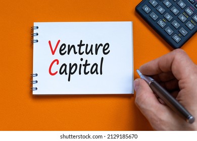 VC venture capital abbraviation symbol. Concept words VC venture capital on white note. Businessman hand, calculator. Beautiful orange background. Copy space. Business and VC venture capital concept.